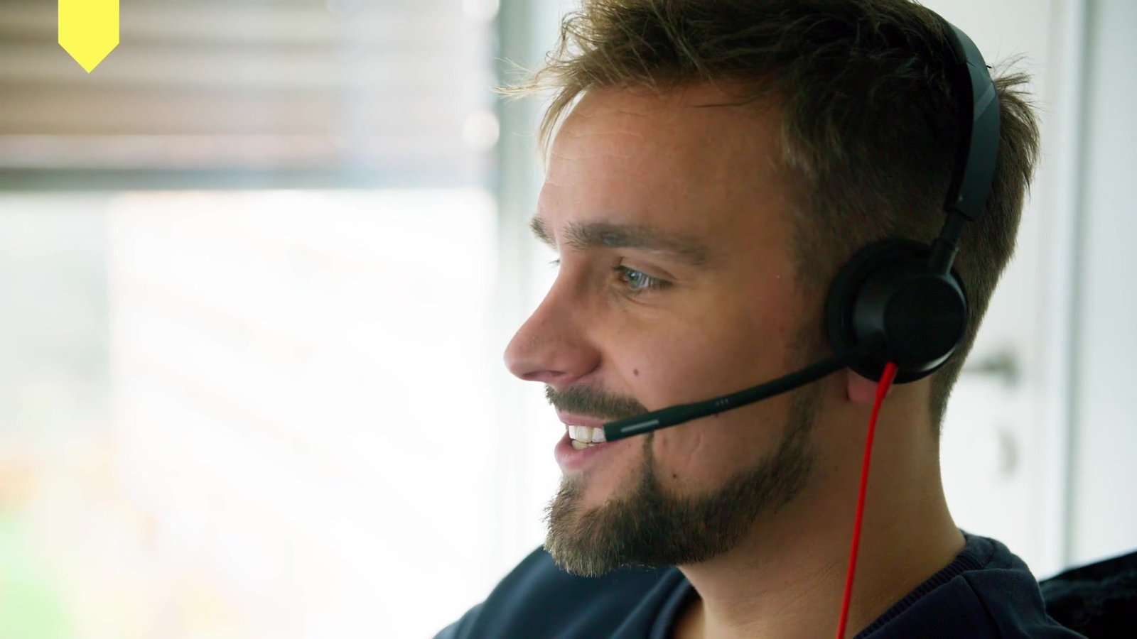 Lächelnder Mitarbeiter mit Headset im Kundenservice des Jobcenters