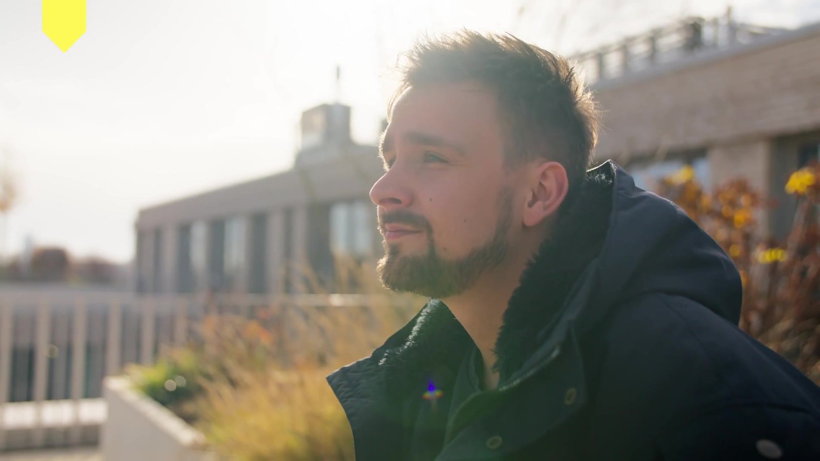Nachdenklicher junger Mann im warmen Gegenlicht auf der Dachterrasse